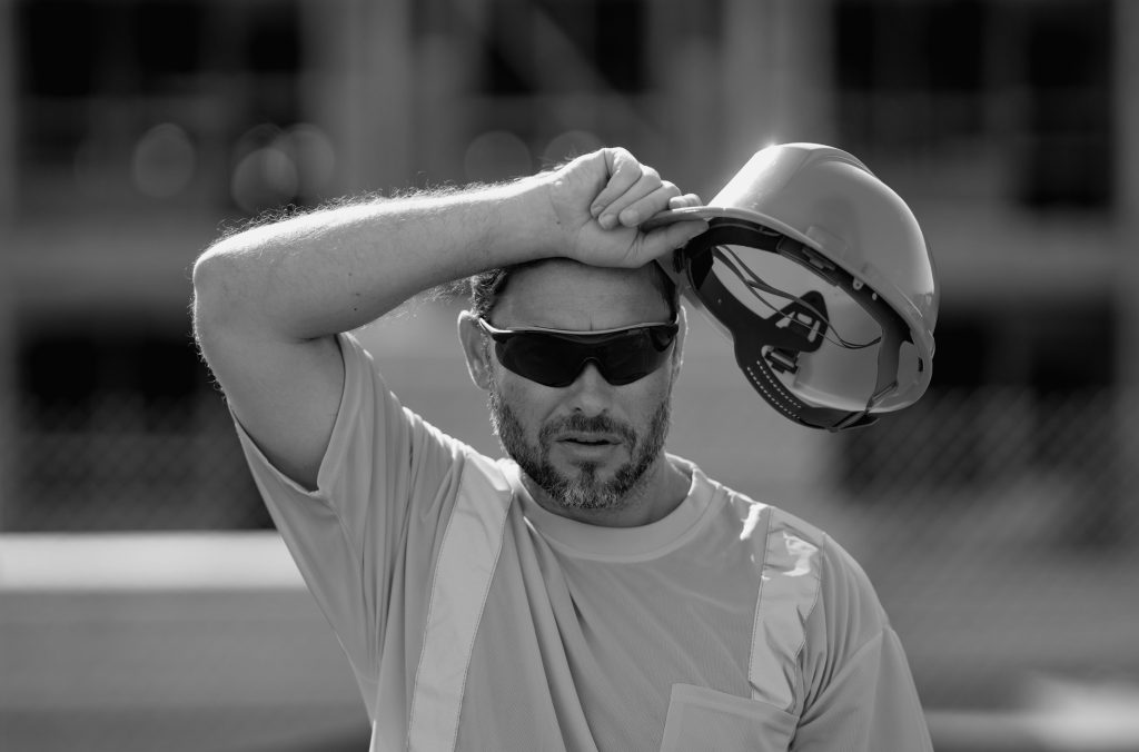 Outside tired construction worker dealing with heat hazards