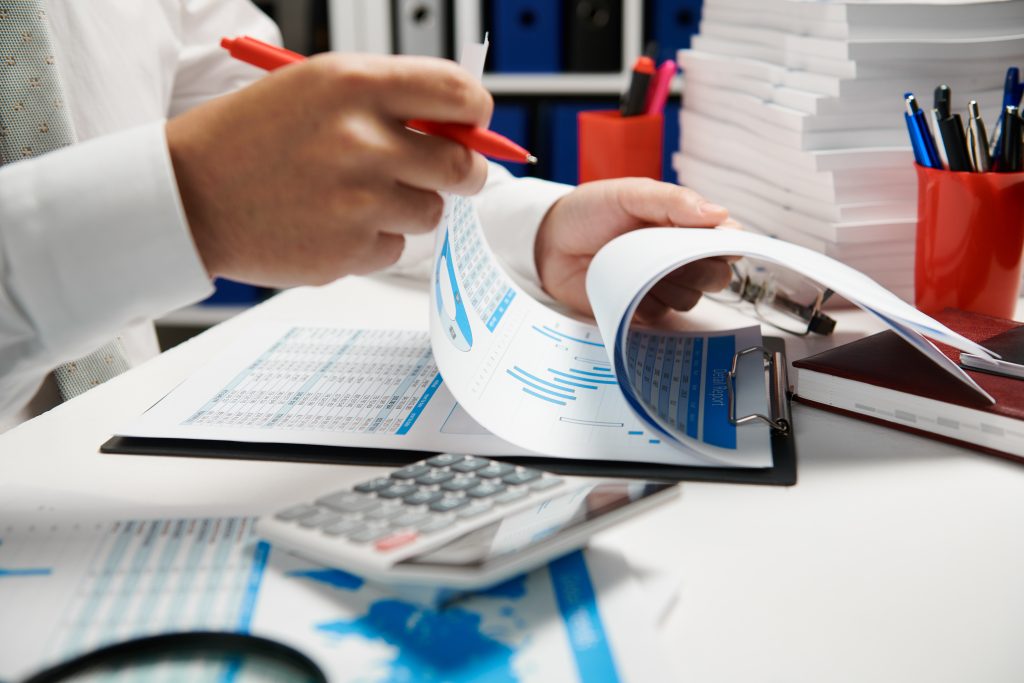 Businessman working and calculating, reads and writes reports. Office employee, table closeup. Business financial accounting concept.