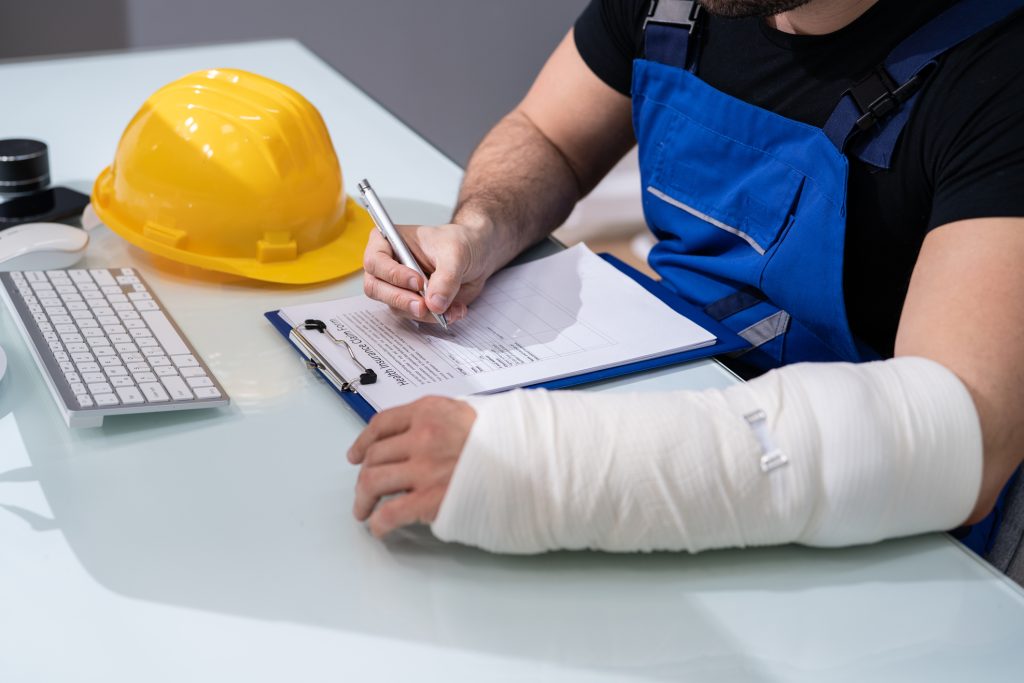 Man with bandaged arm filling out a paper
